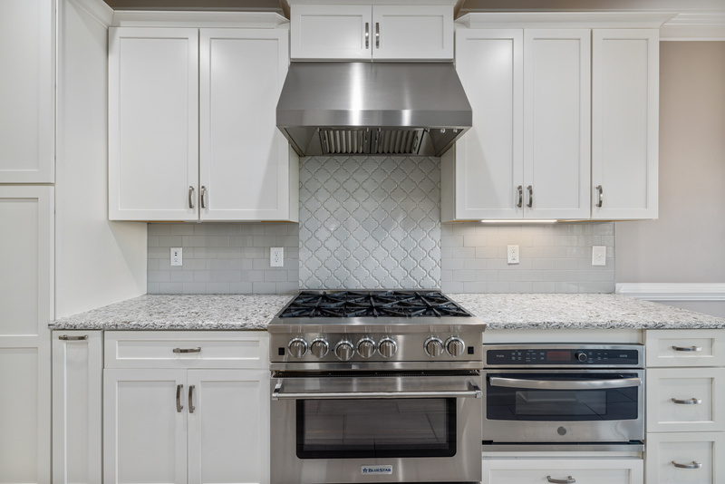 White Wooden Kitchen Cabinets Over Stainless Steel Gas Stove and Oven